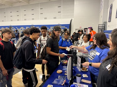 Kelly George and Andrea Hill from the Fresno DA's Office, at a school fair booth, actively engaging with students exploring opportunities and resources for their future.