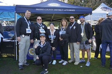 District Attorney employees strike a victorious pose at the Support Blue Run, proudly displaying their hard-earned medals and showcasing their dedication.